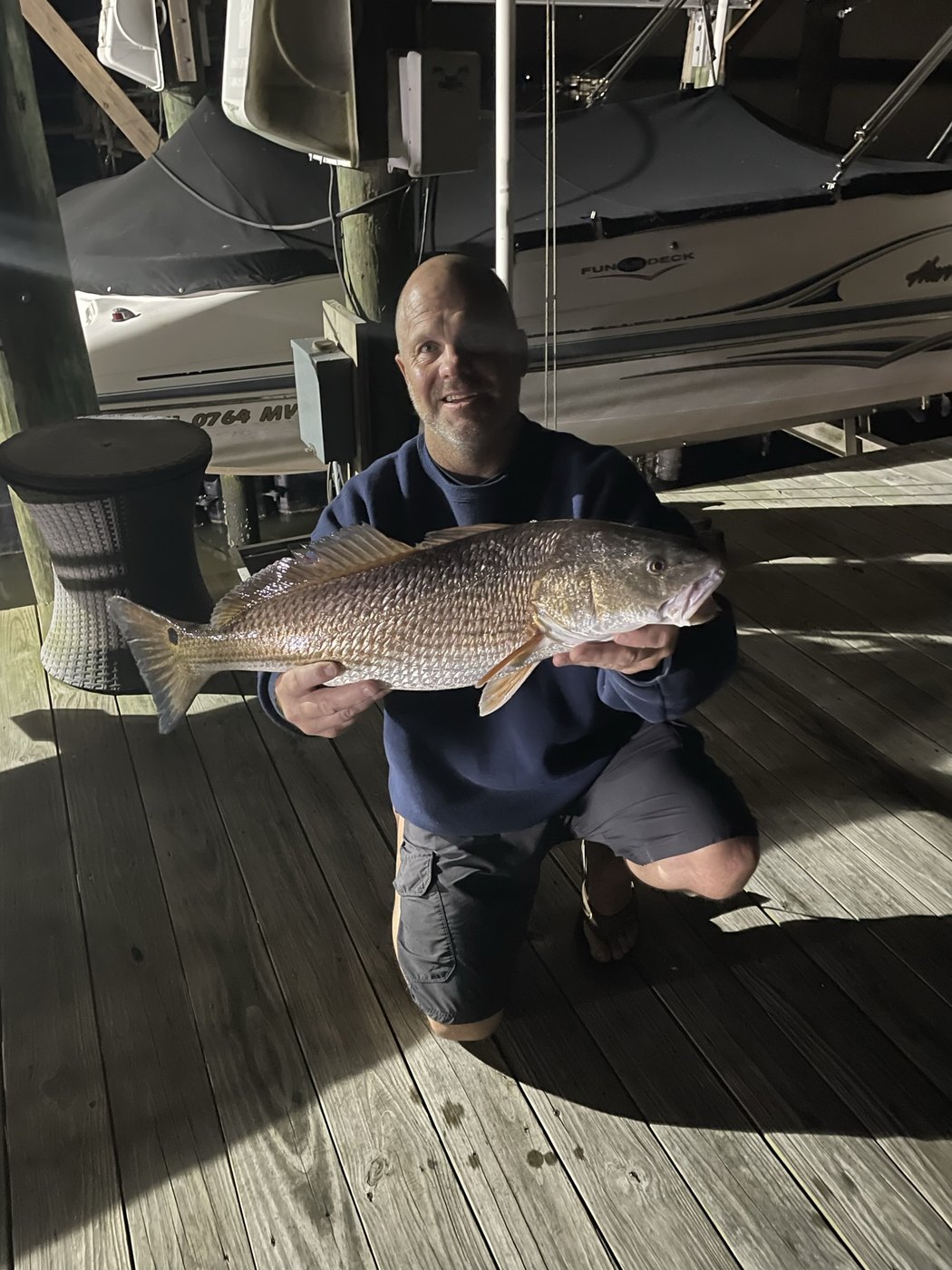 Angler holding a redfish on a dock at night