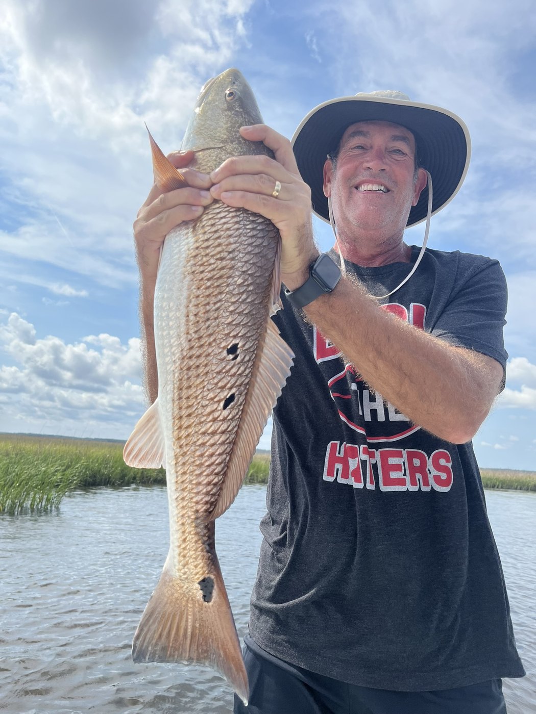 Angler holding a large redfish beside the marsh